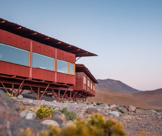 A modern lodge set in a dry, rocky landscape at dusk.