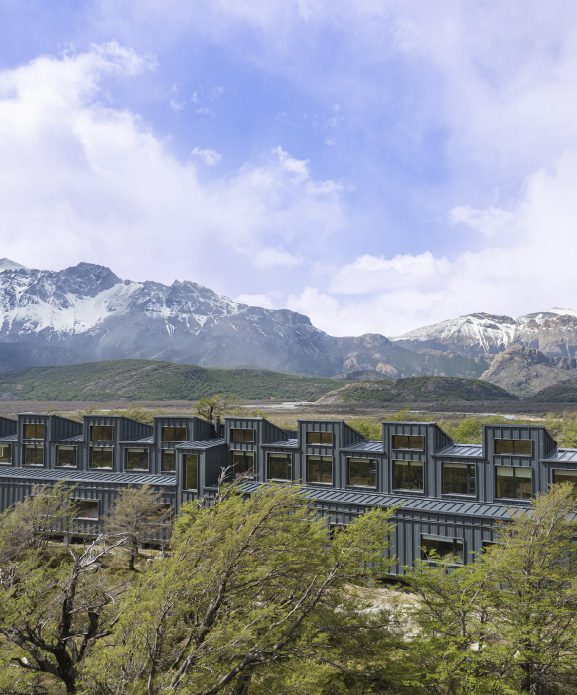Explora El Chaltén lodge in Argentine Patagonia, overlooking a glacier‑fed lake with the dramatic granite peaks of Los Glaciares National Park in the background.
