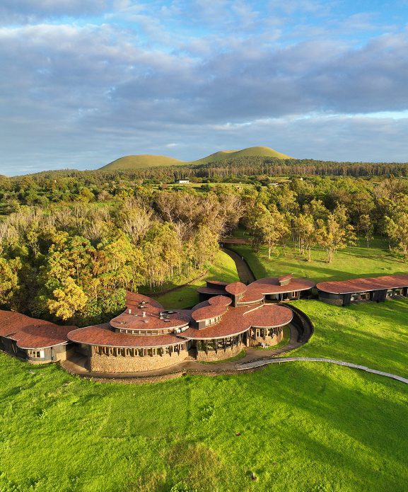 Explora Rapa Nui luxury lodge on Easter Island, featuring circular wooden architecture set amid volcanic terrain and native vegetation.