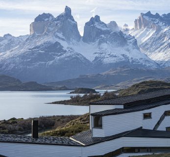 Explora Torres del Paine lodge overlooking a lake, with the iconic granite peaks of Torres del Paine rising in the background.
