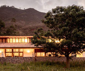 Luxury lodge in Peru’s Sacred Valley at dusk, featuring warm interior lighting, stone walls, and surrounding Andean landscape.