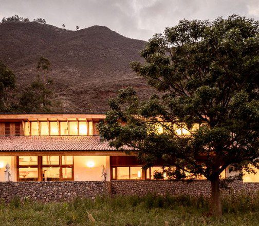 Luxury lodge in Peru’s Sacred Valley at dusk, featuring warm interior lighting, stone walls, and surrounding Andean landscape.