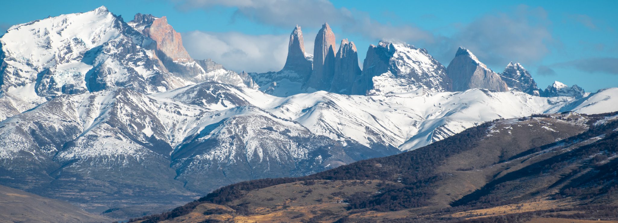 http://A%20dramatic%20range%20of%20snow-capped%20mountains%20with%20sharp%20peaks%20rising%20under%20a%20clear%20blue%20sky.