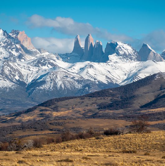 http://A%20dramatic%20range%20of%20snow-capped%20mountains%20with%20sharp%20peaks%20rising%20under%20a%20clear%20blue%20sky.
