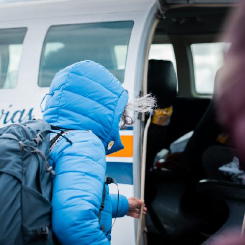 A traveler in a blue jacket steps into a van in cold weather.