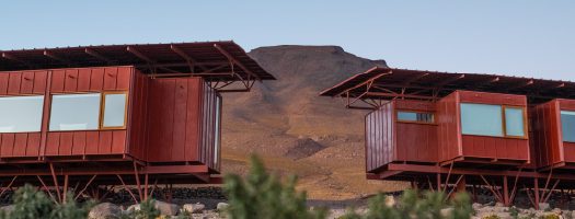 Close view of raised desert lodge with a mountain backdrop.
