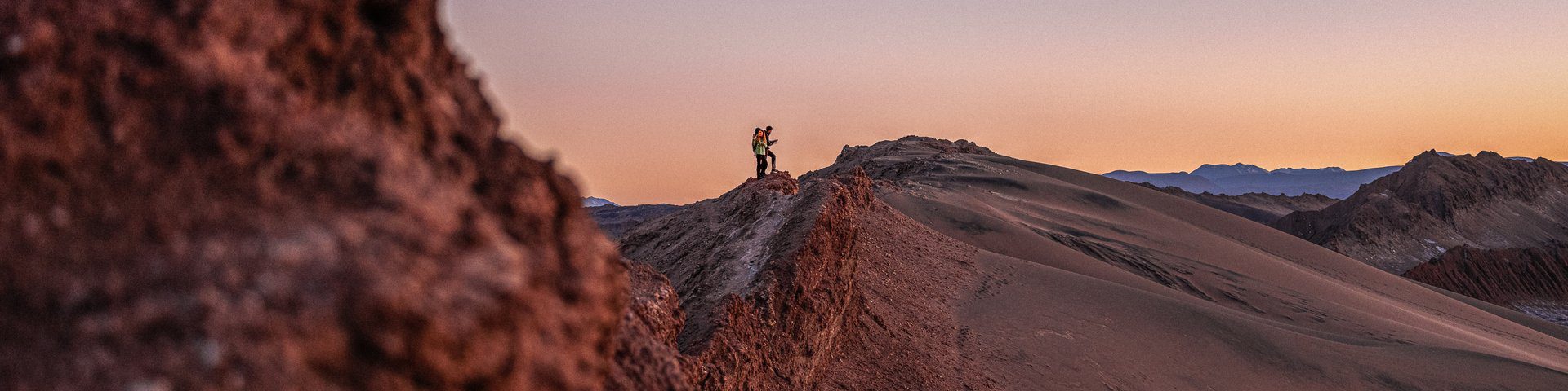 Explorador no cume rochoso do deserto do Atacama ao pôr do sol, Chile