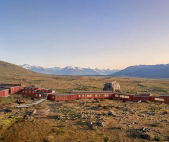 Patagonia hotel complex set in an open steppe landscape with mountain views under a clear sky, overlooking Perito Moreno Glacier