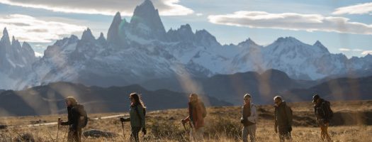 Group of hikers walking through Patagonian plains with Mount Fitz Roy rising in the background
