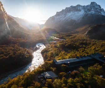 Aerial view of a luxury lodge beside a river surrounded by autumn forests in El Chaltén, Patagonia, Argentina