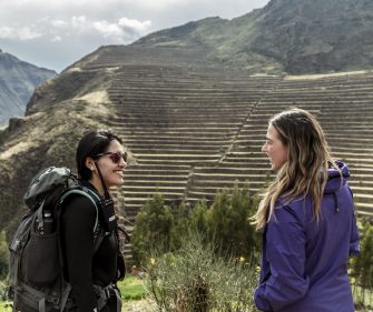 Travelers stand before expansive Inca agricultural terraces in Peru’s Sacred Valley, highlighting ancient engineering and mountain scenery.