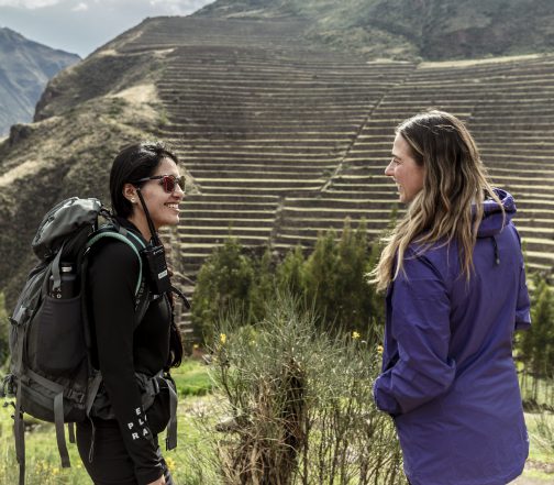Travelers stand before expansive Inca agricultural terraces in Peru’s Sacred Valley, highlighting ancient engineering and mountain scenery.