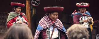 Traditional Andean artisans demonstrate cultural practices for visitors in Peru’s Sacred Valley, wearing vivid handmade textiles.